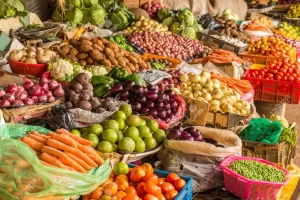 fresh produce items in the market among them onions, tomatoes and carrots.