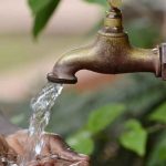 A BOY WASHING HANDS ON A WATER TAP