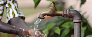 A BOY WASHING HANDS ON A WATER TAP