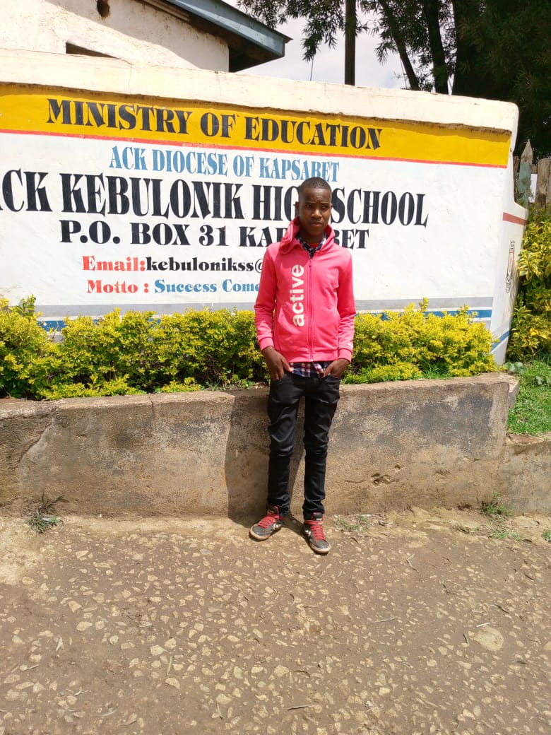 Brian Momanyi poses for a photo at his former High School. He is yet to join university for lack of school fees.