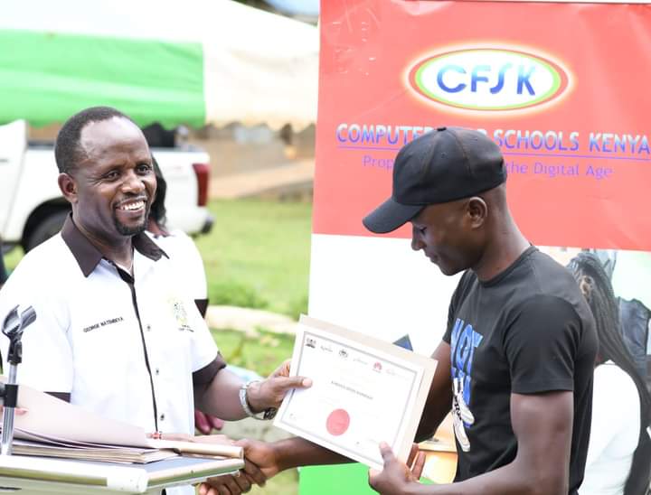 Natembeya presents a certificate to one of the graduands.