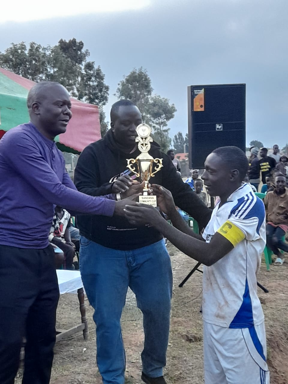 Sandana Community Initiative founder and chairperson Gil Nasiali (left) handing the trophy to the winning team on December 31, 2023. 