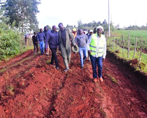 Governor Bii with his delegation walks in a poor road