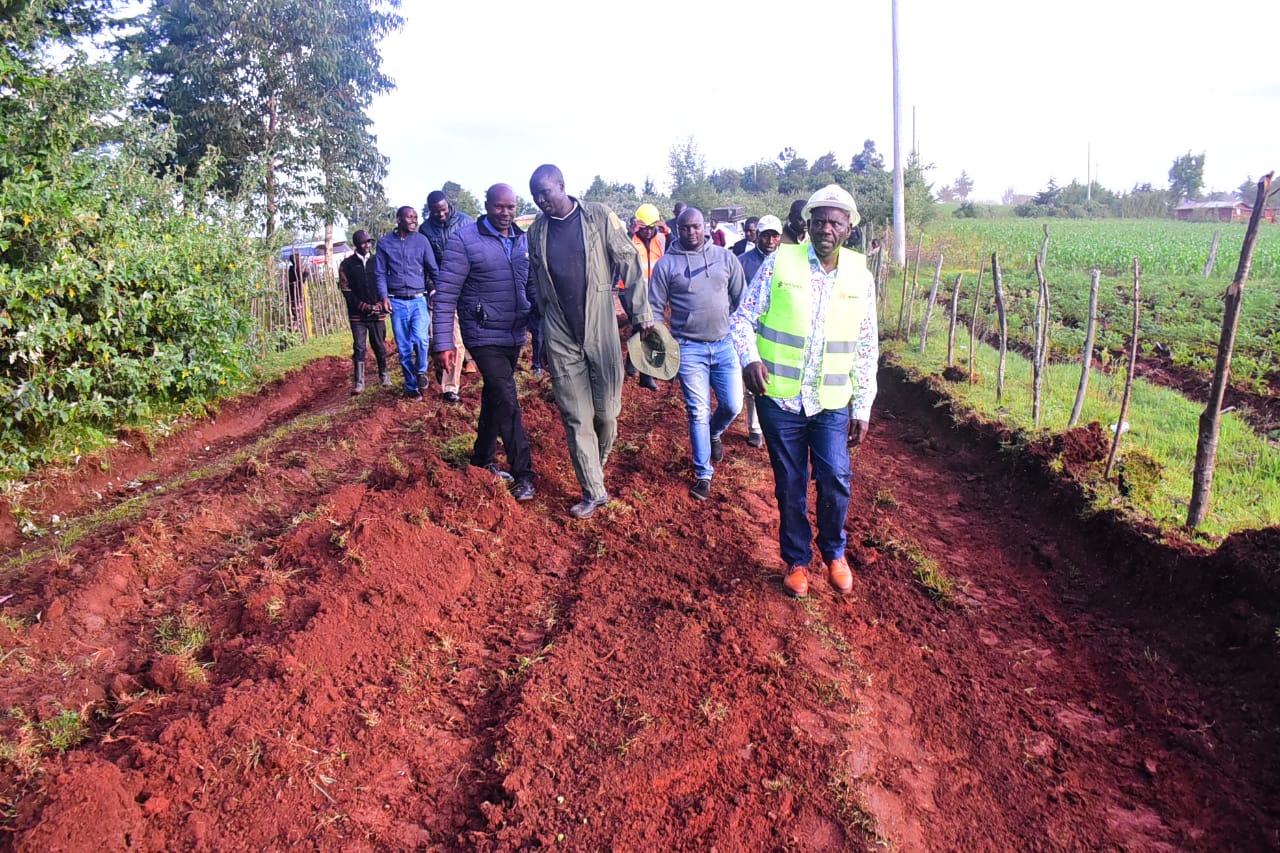 Governor Bii with his delegation walks in a poor road