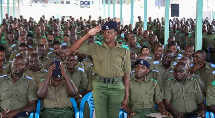 A female DCI officer salutes with other looking on