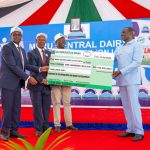 President Ruto hands over a dummy cheque to officials of during the Meru Cooperative Union