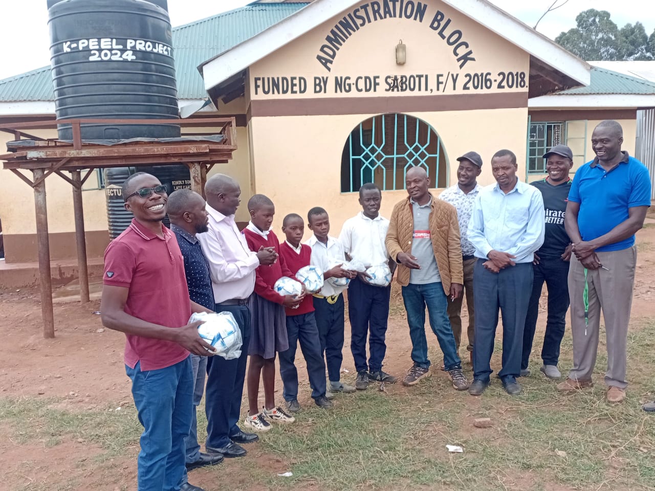 Pupils and teachers of a primary school in Saboti Constituency, Trans Nzoia County holding balls donated by FKF Trans Nzoia branch.