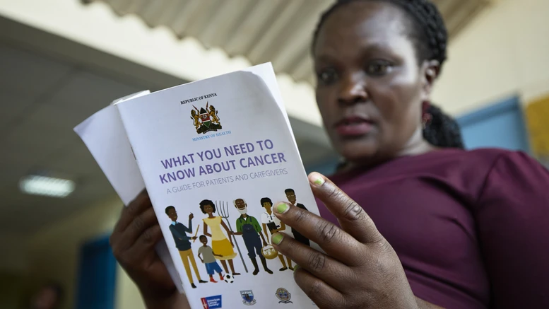 Woman holds breast cancer awareness booklet.