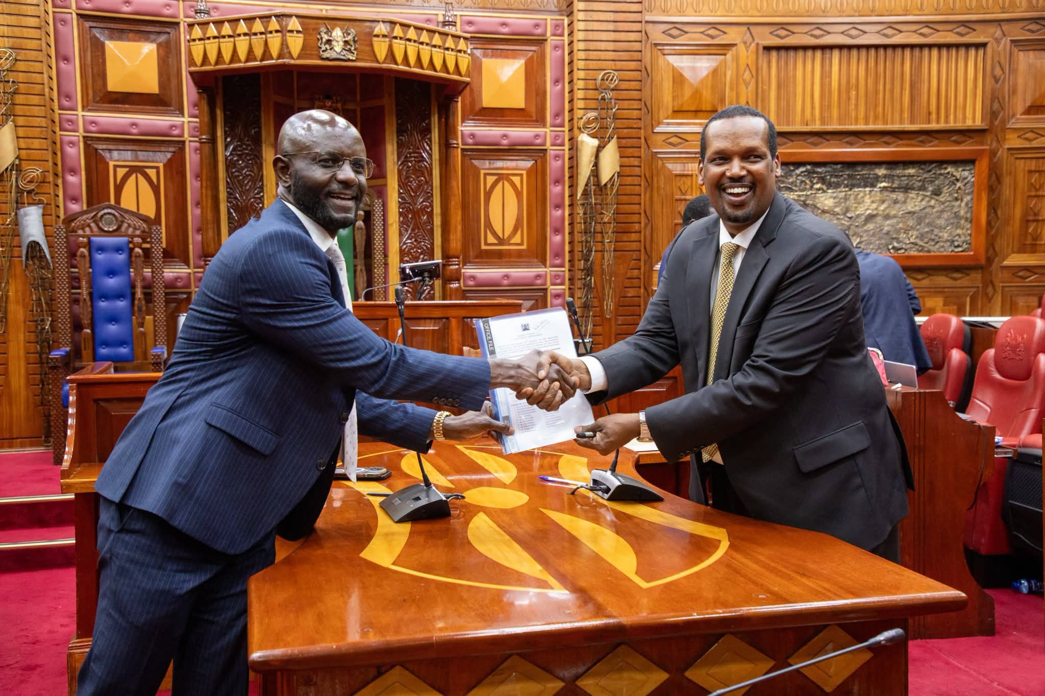 Mediation committee co-chair Samuel Atandi and Ali Roba shake hands after reaching agreement